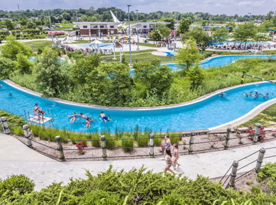A vibrant water park scene with a lazy river, greenery, and people enjoying summer fun, evoking joy and relaxation.