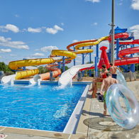 A vibrant water park scene with colorful slides, a clear pool, and people enjoying a sunny, adventurous day.
