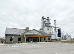 A modern small building with large windows and silos behind it evokes nostalgia and calmness in a muted industrial setting.