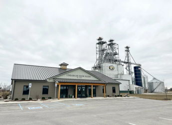 A modern small building with large windows and silos behind it evokes nostalgia and calmness in a muted industrial setting.