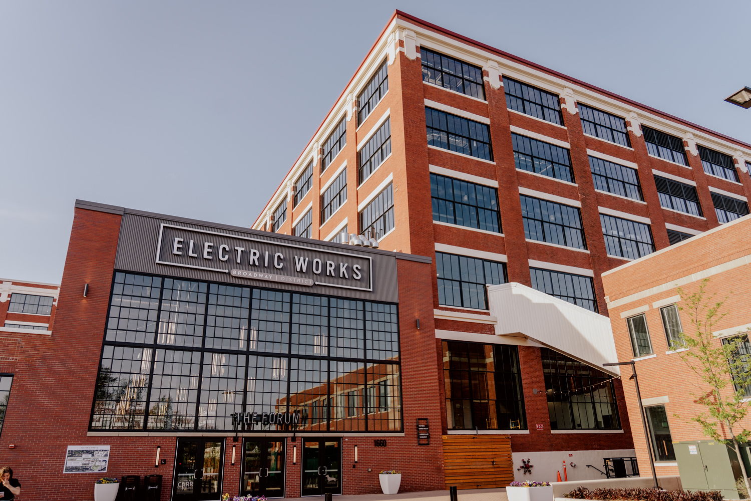 Modern building labeled "ELECTRIC WORKS" with brick facade, large windows, and an inviting atmosphere for innovation.