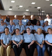 Group of smiling individuals in light blue shirts sit on a staircase, conveying unity, happiness, and a sense of community.