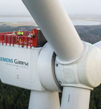 A wind turbine nacelle with workers on a platform, set in lush greenery, symbolizes clean energy and teamwork in nature.