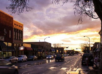 Sunset street scene with vibrant colors, wet pavement, and inviting atmosphere, evoking tranquility and small-town charm.
