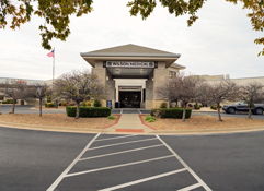 Modern building labeled "WILSON WESLEY" with stone accents, bare trees, and neat landscaping, conveying stability and warmth.