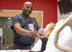 A smiling healthcare professional interacts with a young patient in a hospital, conveying warmth, care, and compassion.