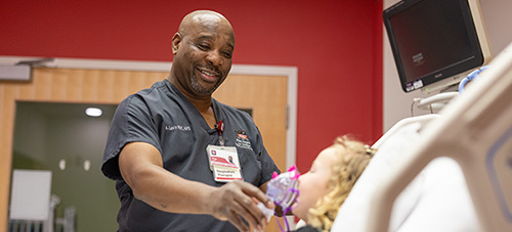 A smiling healthcare professional interacts with a young patient in a hospital, conveying warmth, care, and compassion.