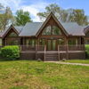 Log cabin-style house in a green setting, featuring a triangular roof, large windows, and a cozy, tranquil atmosphere.