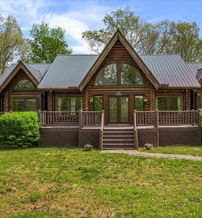 Log cabin-style house in a green setting, featuring a triangular roof, large windows, and a cozy, tranquil atmosphere.