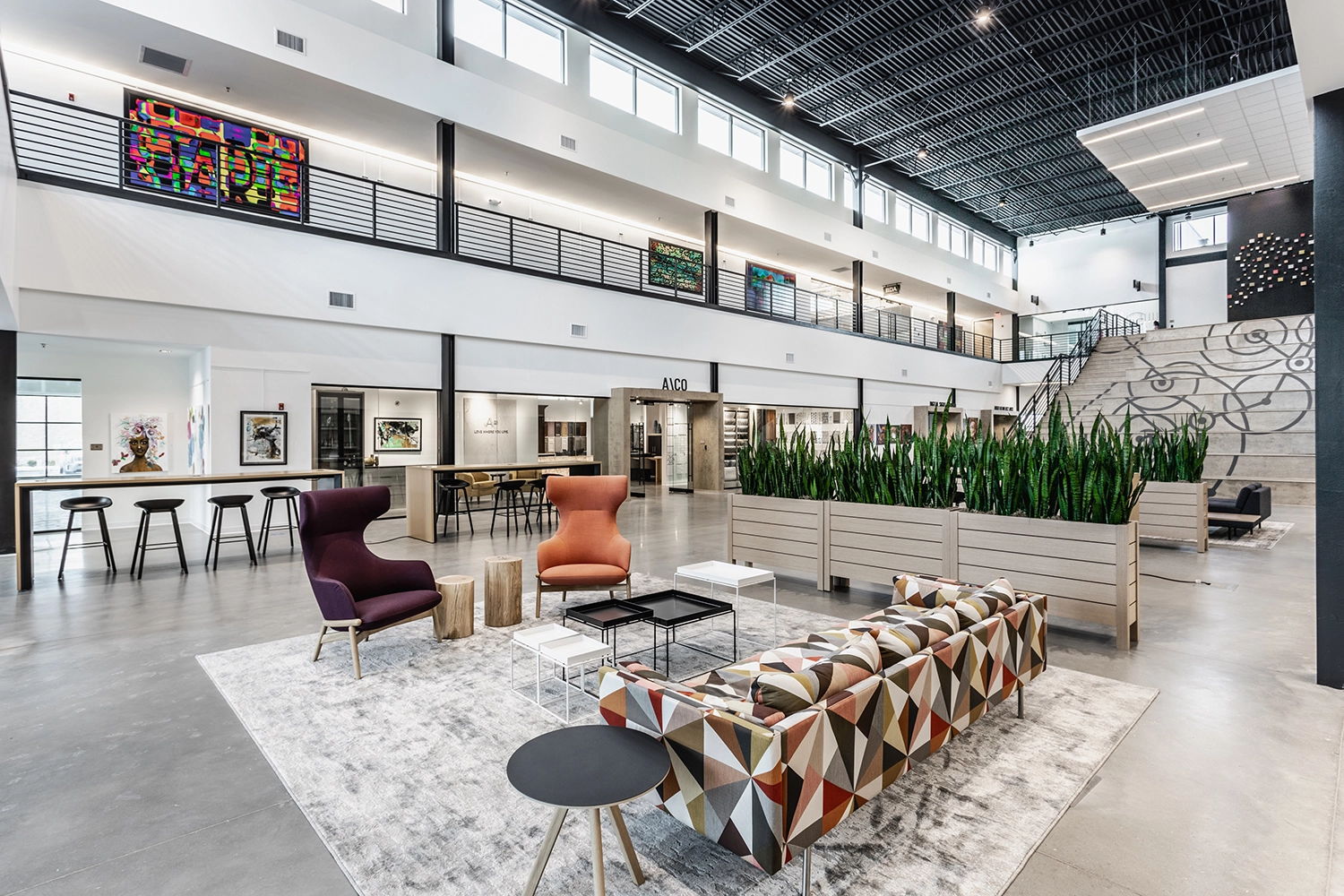 Modern lobby with high ceilings, vibrant decor, plants, and unique furniture, creating a welcoming and stylish atmosphere.