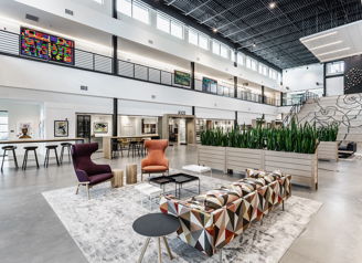 Modern lobby with high ceilings, vibrant decor, plants, and unique furniture, creating a welcoming and stylish atmosphere.