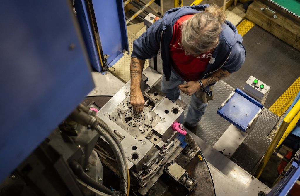 A focused worker engages with machinery in a factory, surrounded by tools, conveying dedication and craftsmanship.