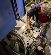 A focused worker engages with machinery in a factory, surrounded by tools, conveying dedication and craftsmanship.
