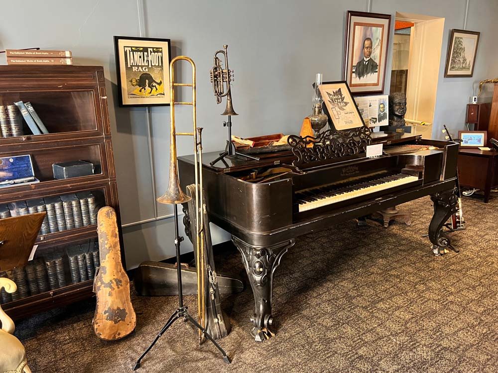 A cozy, vintage room with an antique piano, musical instruments, books, and warm lighting evokes nostalgia and creativity.