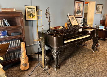 A cozy, vintage room with an antique piano, musical instruments, books, and warm lighting evokes nostalgia and creativity.
