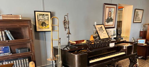 A cozy, vintage room with an antique piano, musical instruments, books, and warm lighting evokes nostalgia and creativity.