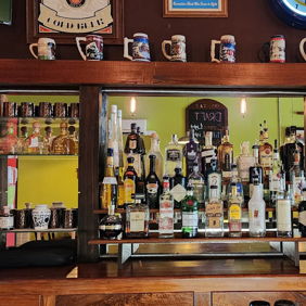 Wooden bar with colorful bottles, mirror, and decor creating a cozy, inviting atmosphere for socializing and relaxation.