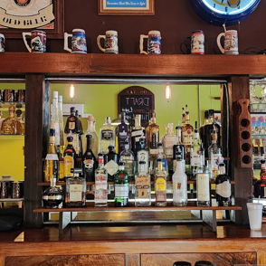 Wooden bar with colorful bottles, mirror, and decor creating a cozy, inviting atmosphere for socializing and relaxation.