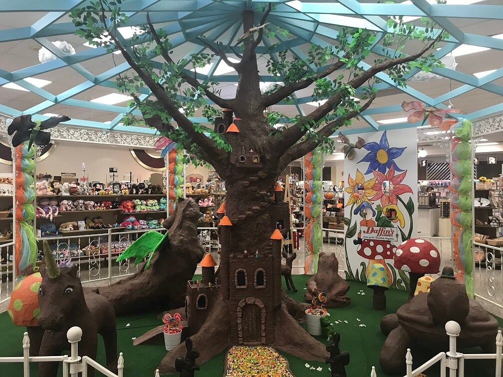 Whimsical, vibrant playground with a large artistic tree, colorful mushrooms, a castle, and cute fantasy animal figures.