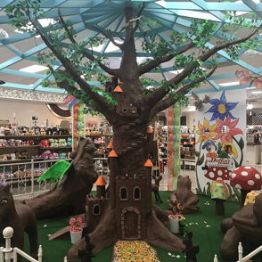 Whimsical, vibrant playground with a large artistic tree, colorful mushrooms, a castle, and cute fantasy animal figures.