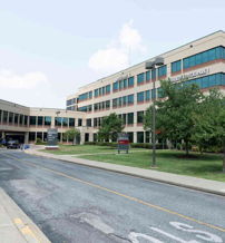 Modern hospital building with large windows, green surroundings, and accessible entrance, evoking safety and tranquility.