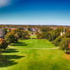 Vibrant campus scene with autumn foliage, green lawns, historic buildings, and a clear blue sky, evoking calmness and nostalgia.