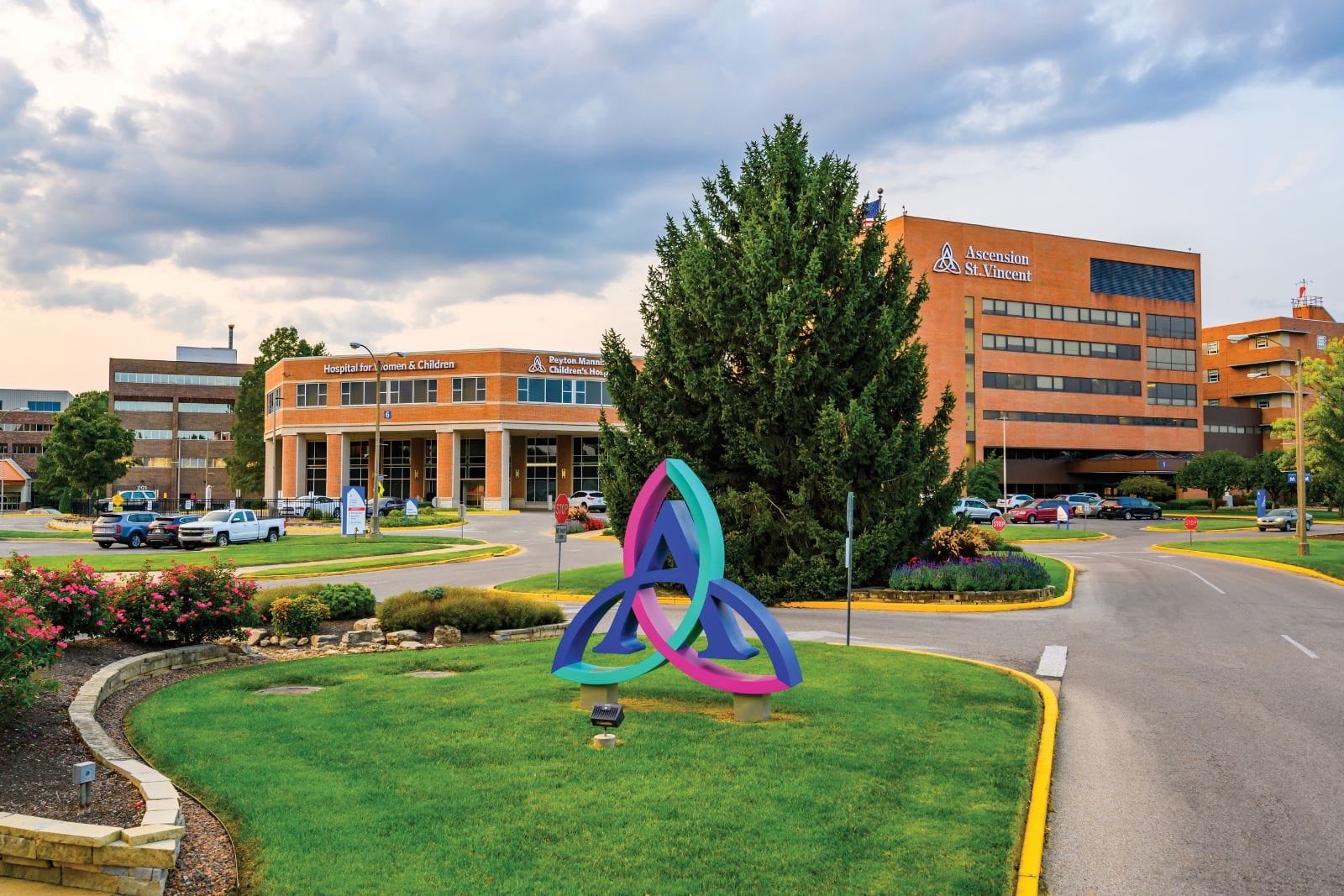 Well-kept outdoor area with a colorful sculpture, green grass, and landscaped flowerbeds, evoking tranquility and community.