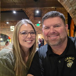 A happy couple poses for a selfie in a cozy, rustic setting, conveying warmth, joy, and a sense of togetherness.