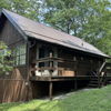 Cozy cabin in lush greenery, with rustic charm and inviting porch, evoking tranquility and a peaceful natural retreat.
