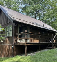 Cozy cabin in lush greenery, with rustic charm and inviting porch, evoking tranquility and a peaceful natural retreat.