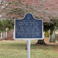 Historical marker for Wilbur Wright in a grassy area, evoking nostalgia and inspiration for aviation achievements.