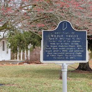 Historical marker for Wilbur Wright in a grassy area, evoking nostalgia and inspiration for aviation achievements.