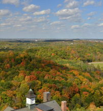 Vibrant fall landscape with colorful trees and clouds, highlighting a building, evoking tranquility and appreciation for nature.