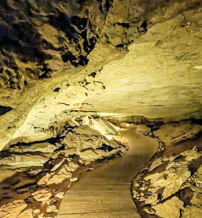 Cave interior with rugged rocks and a warm glow, inviting exploration along a smooth, winding path into the unknown.