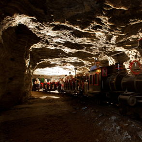 A colorful train travels through a warmly lit rock tunnel, evoking adventure and nostalgia in a whimsical, inviting atmosphere.