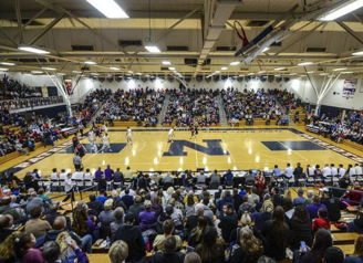 A crowded basketball gym filled with excited fans, creating a vibrant atmosphere of community and anticipation.