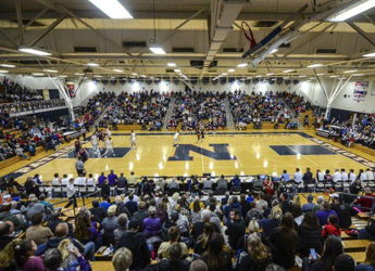 A crowded basketball gym filled with excited fans, creating a vibrant atmosphere of community and anticipation.