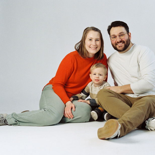 A joyful family sits together, radiating love and comfort, with bright colors and cheerful expressions in a cozy scene.
