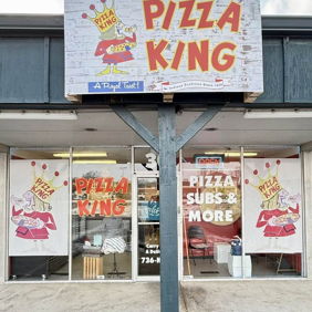Colorful "Pizza King" storefront with bright graphics, large windows, inviting atmosphere, evoking warmth and nostalgia.
