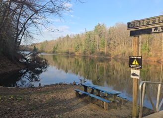A peaceful river scene at Griffin Lake, framed by trees, with a picnic table for enjoying nature's tranquility.