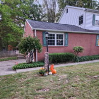 Cozy brick house with green shutters, pumpkins, and seasonal decor, evoking warmth and nostalgia for fall.