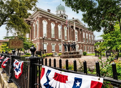 Historic building with classic architecture, festive bunting, statue, and lush trees, evoking pride and celebration.