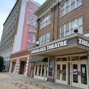 Exterior of Douglass Theatre with classic architecture, vibrant marquee, and striped awnings, evoking nostalgia and excitement.