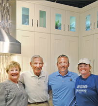Four smiling individuals stand in a modern kitchen, exuding warmth, joy, and a sense of togetherness.