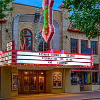 Vintage theater facade with colorful neon lights, exuding nostalgia and community spirit under a twilight sky.