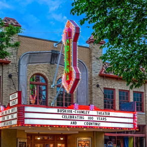 Vintage theater facade with colorful neon lights, exuding nostalgia and community spirit under a twilight sky.