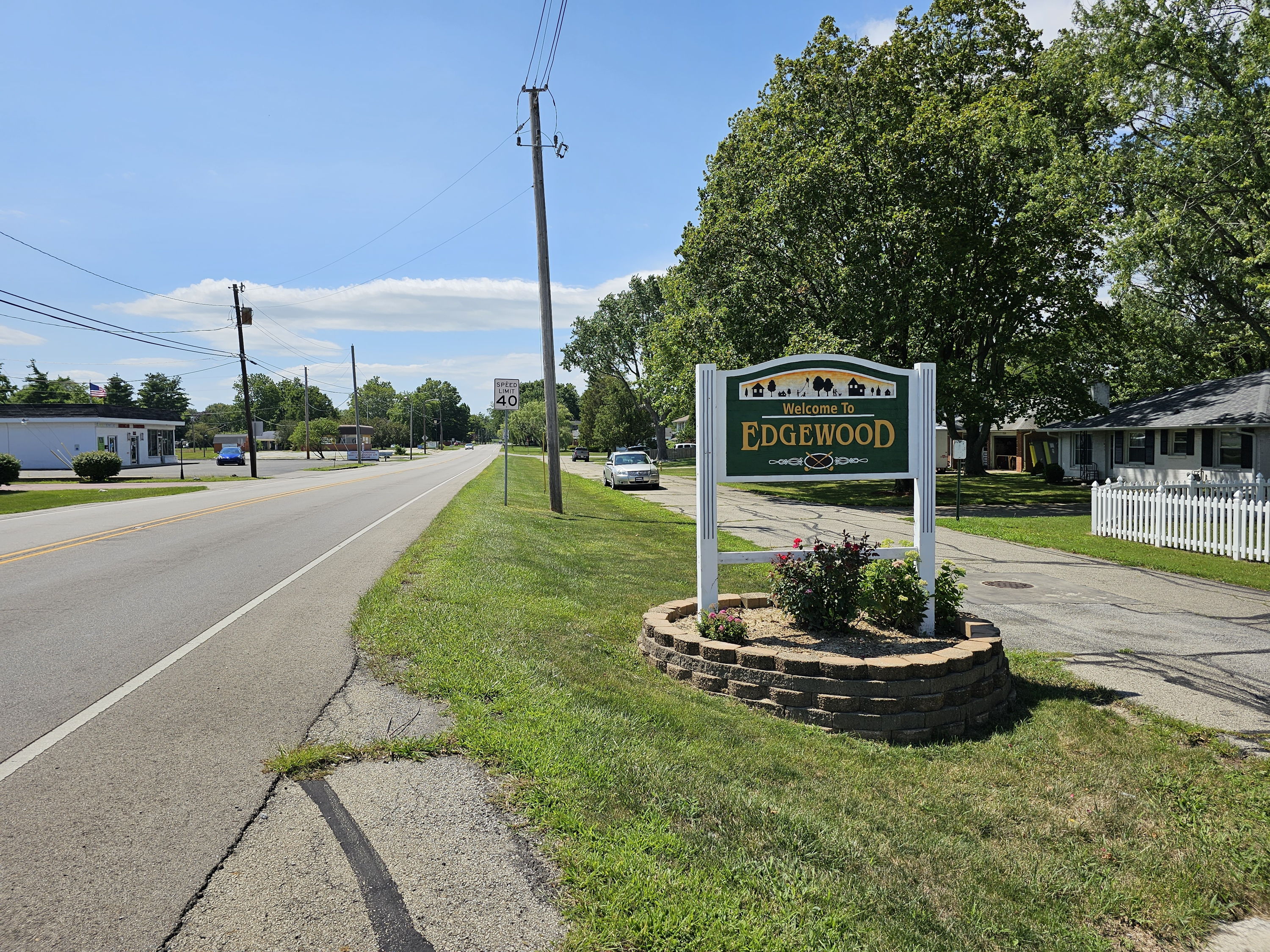 Welcoming sign for "Edgewood" along a peaceful road, surrounded by vibrant flowers and a friendly neighborhood atmosphere.