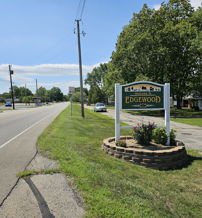 Welcoming sign for "Edgewood" along a peaceful road, surrounded by vibrant flowers and a friendly neighborhood atmosphere.