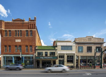 A vibrant urban scene with diverse buildings, a bright sky, and vehicles, blending historical and modern architectural styles.