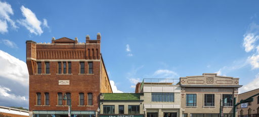 A vibrant urban scene with diverse buildings, a bright sky, and vehicles, blending historical and modern architectural styles.